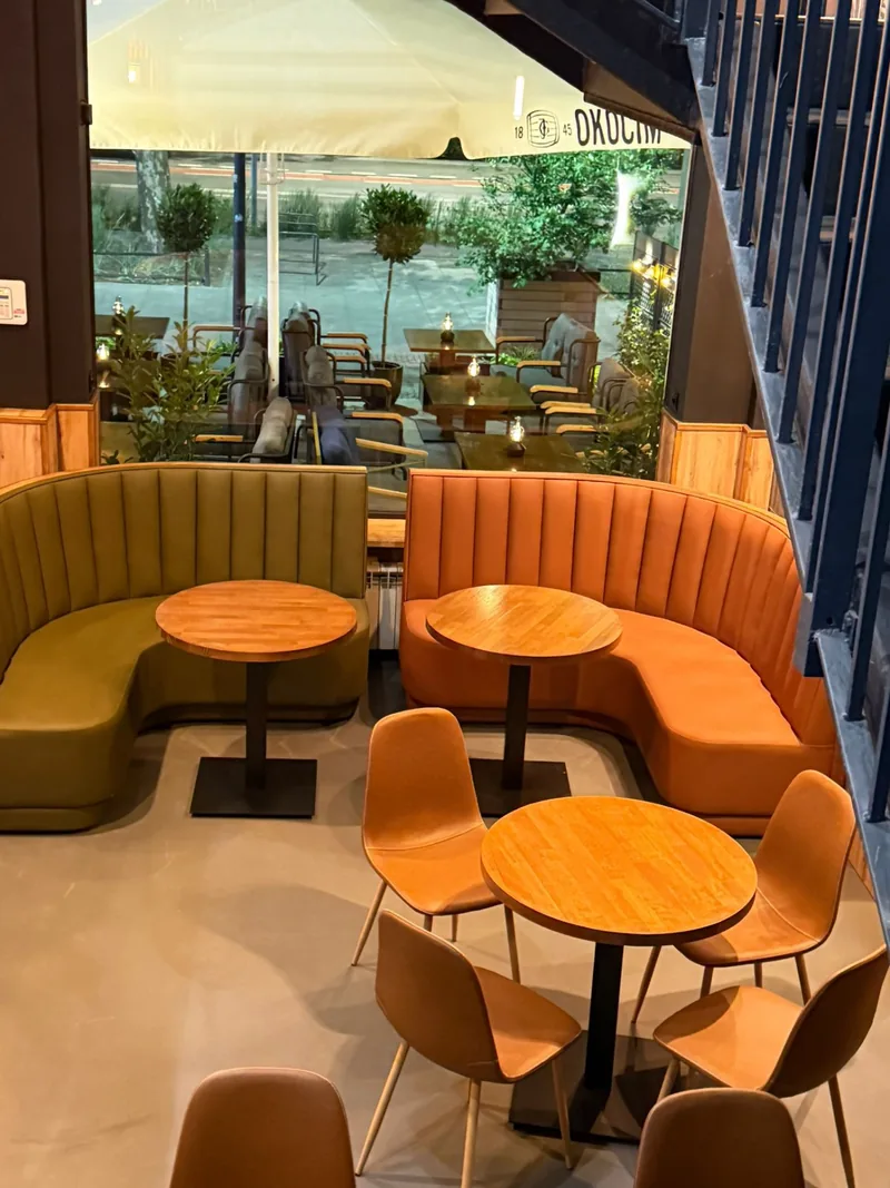 Łukowe skórzane kanapy i orzechowe stoliki we wnętrzu Fajka Bar Lounge